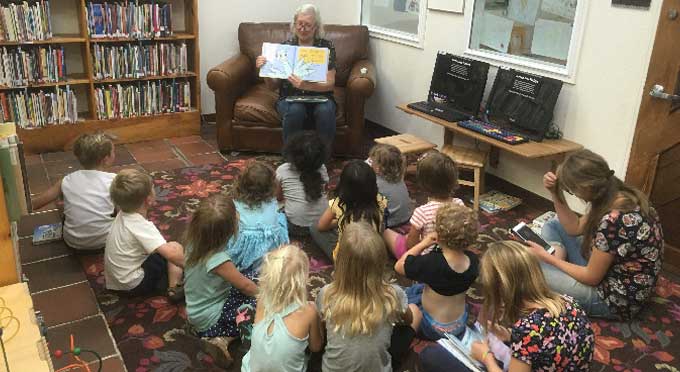 Woman reading at storytime to children in library.