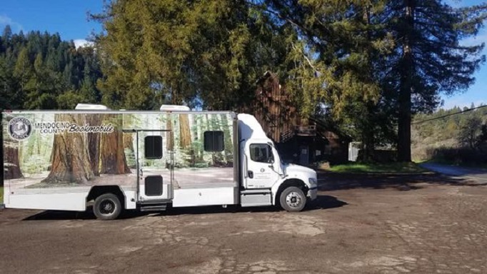 Bookmobile parked in front of Redwood trees.