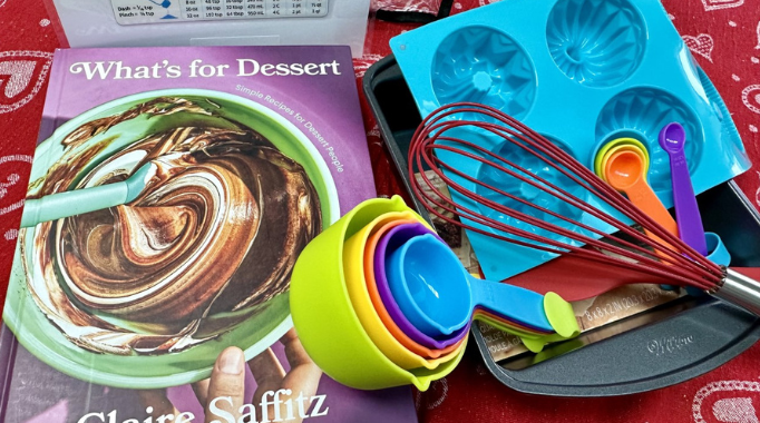 Baking kit with cookbook, measuring cups, pan, muffin molds and measuring chart.