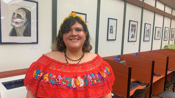 Ukiah staff member standing in front of her artwork on exhibit at the library.