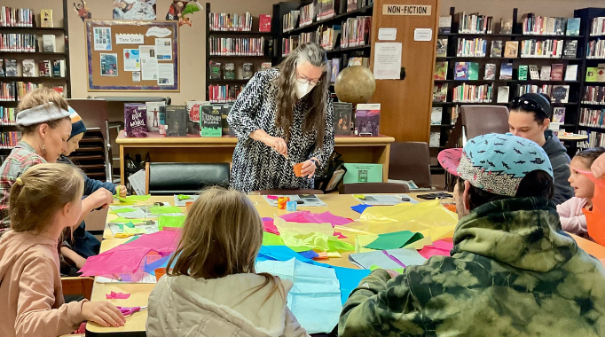 Woman and children doing a craft project at the library.