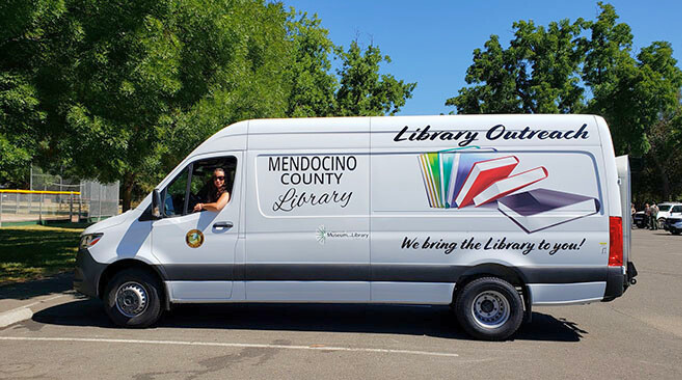 Library Outreach van with woman in drivers seat in parking lot.