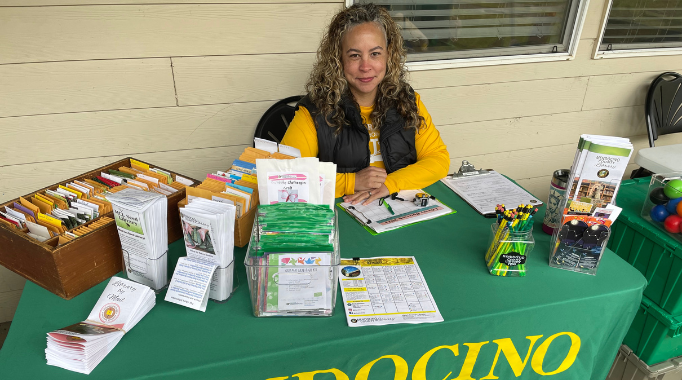 Woman smiling sitting at a table with seed packets and brochures.