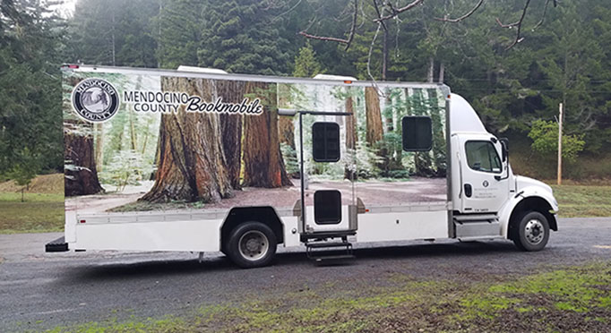 Bookmobile parked on roadside at Chamberlain Creek with trees in background.