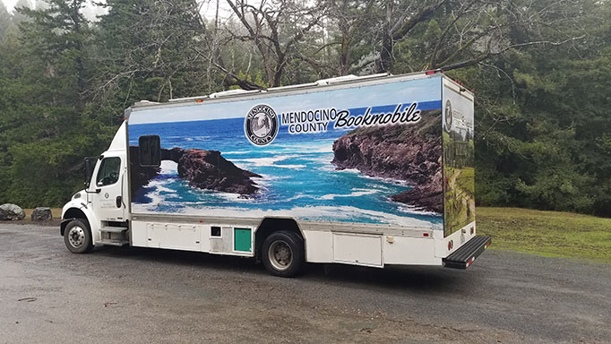 Bookmobile parked on roadside at Chamberlain Creek with trees in background.
