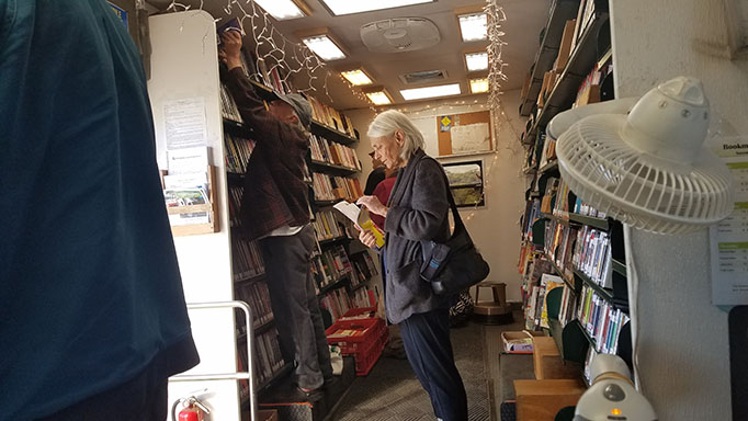 Adults inside the Bookmobile looking at books.